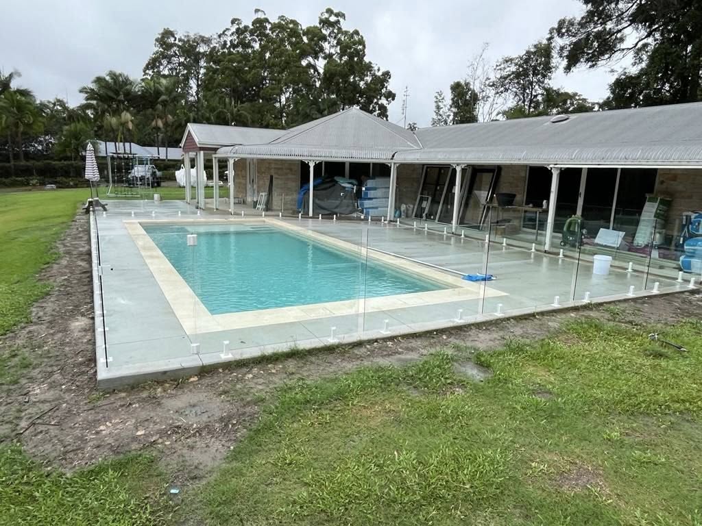 Large frameless glass pool fence with white spigots at an acreage homestead
